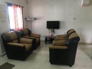 a living room with two chairs and a tv at ECR Holiday in Chennai