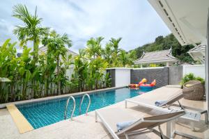 an outdoor swimming pool with two chairs and a swimming pool at Kamala Garden View Villa 3 Bdr in Kamala Beach