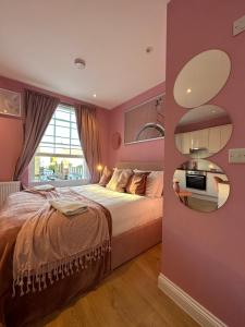 a bedroom with a bed and a pink wall at Gloucester Place - Baker Street in London