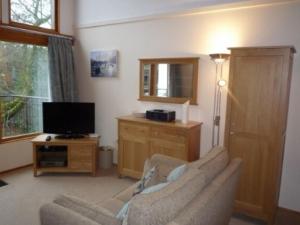 a living room with a couch and a television at Keswick Bridge 17 in Keswick