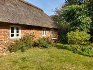 an old brick house with a thatched roof and a yard at Ringkøbing Fjord B&B in Skjern