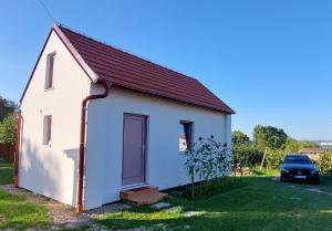 ein kleines weißes Haus mit einem Auto im Hof in der Unterkunft Pavlov24 - Domeček u potoka in Pavlov