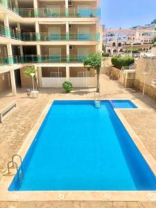 Modern apartment with pool close to the beach. في بينييسكولا: مسبح ازرق كبير امام مبنى