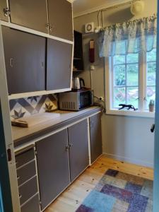 a kitchen with gray cabinets and a microwave at Fjord peace in Skodje