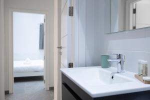 a white bathroom with a sink and a mirror at Valletta Waterfront Backyard Flat by Arco Collection in Il-Furjana +58 photos