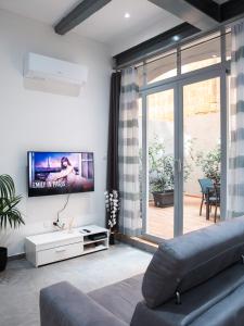 ein Wohnzimmer mit einem Sofa und einem Flachbild-TV in der Unterkunft Valletta Waterfront Backyard Flat in Floriana