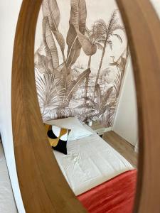 d'un miroir reflétant un lit orné d'une fresque murale de palmiers. dans l'établissement L’évasion - Studio cosy en centre ville, à Rennes