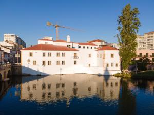 a white building sitting in the water next to buildings at Vila Gale Collection Tomar in Tomar