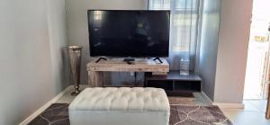 a living room with a television and a white couch at Grassland 4 (Townhouse) in Bloemfontein