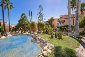 a swimming pool in a yard with palm trees at Sunshine Apartments in San Miguel de Abona