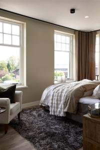 a bedroom with a bed and two windows at Brasserie Spoorhuis Mijdrecht in Mijdrecht