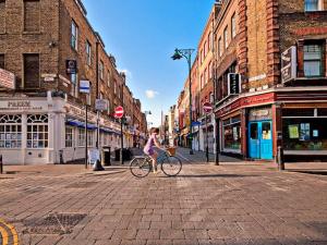 a woman riding a bike on a city street at Shoreditch apartment with lovely garden in London