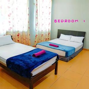 バヤンレパスにあるMuslim Suite Home @ Airport Bayan Lepas Penangのベッド2台が備わる客室で、ベッドサインが付いています。