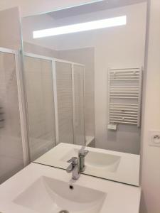 ein weißes Badezimmer mit einem Waschbecken und einem Spiegel in der Unterkunft Grande Chambre Neuve Parking prive Cergy RER in Cergy