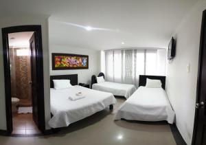 a hotel room with two beds and a mirror at Hotel Andinos Plaza Pitalito in Pitalito