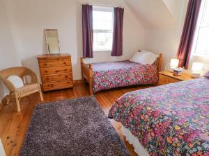 a bedroom with two beds and a dresser and a mirror at Craiglea Cottage in Coleraine