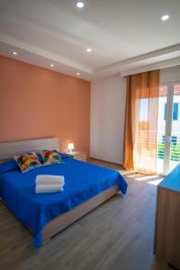 una camera con un letto blu e una grande finestra di Stella Marina Apartment - Sea View, close to the beach ad Agnone Bagni