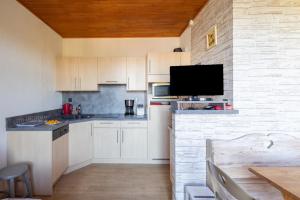 a kitchen with white cabinets and a flat screen tv at Gai Soleil in Saint-Gervais-les-Bains
