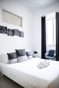 a white bedroom with a large white bed and a chair at Valletta Center Apartment in Valletta