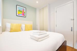 Un dormitorio con una cama blanca con toallas. en Golders Green Serviced Apartments by Concept Apartments, en Londres