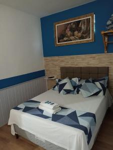 a bedroom with a bed with blue walls and a picture on the wall at Pousada Antares in São Thomé das Letras