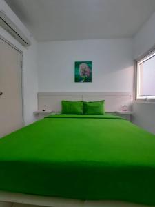 a green bed in a white room with a window at Barata Hotel by Nature's in Tangerang