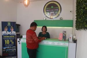 a man and a woman standing at a counter at Barata Hotel by Nature's in Tangerang