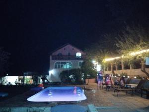 un grupo de personas de pie alrededor de una piscina por la noche en CasaMarinela, en Orşova