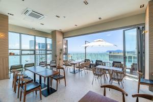 ein Restaurant mit Tischen und Stühlen und Meerblick in der Unterkunft ELBON the stay Haeundae beach in Busan