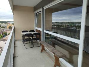 - un balcon avec un banc, une table et des chaises dans l'établissement Elancourt Panorama & Élégance proche sites JO 2024, à Élancourt