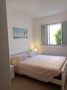 una camera da letto bianca con un letto e due finestre di Casa SantaBarbara a Marina di Ragusa