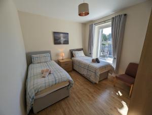 a bedroom with two beds and a window at Derg Valley Apartments in Castlederg