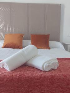 a bed with white sheets and orange pillows at Casa Nina in Linares