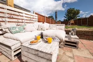 a patio with a white couch and a table with orange juice at Beach Retreat Cottage- huge Garden Child & Dog friendly in Broadstairs