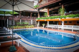 a large swimming pool with chairs and an umbrella at Chandara Boutique Hotel in Vientiane