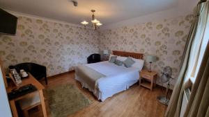 1 dormitorio con cama blanca y papel pintado con motivos florales en Bell Country Inn, en Llanyre