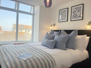 a bedroom with a large bed with a window at Après Beach Apartment Sleeps 4 Penzance in Penzance