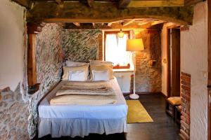 1 dormitorio con 1 cama en una pared de piedra en El nido de la golondrina, en Llanes