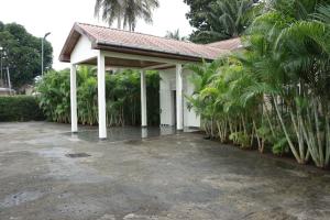 a white pavilion with palm trees in a parking lot at Industria Villa in Ciudad de Malabo