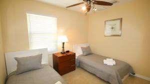 a bedroom with two beds and a ceiling fan at Johns Pass Condo's- Fully Remote in St Pete Beach