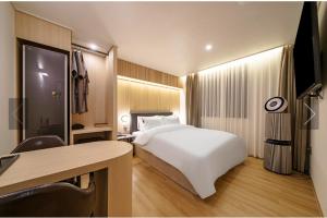um quarto de hotel com uma cama branca e uma secretária em Brown Dot Hotel Yeonsan em Busan