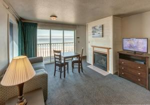 a living room with a couch and a table with a fireplace at Surfside Resort in Rockaway Beach
