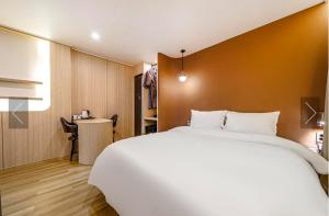 a bedroom with a large white bed and a desk at Brown Dot Hotel Yeonsan in Busan