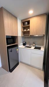a small kitchen with a sink and a refrigerator at Sky Park Laguna 1bdr Lake View in Thalang