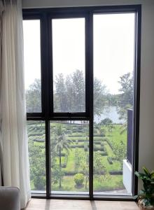 a room with a window looking out at a garden at Sky Park Laguna 1bdr Lake View in Thalang