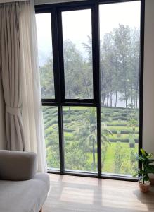 um quarto com uma grande janela com vista para um jardim em Sky Park Laguna 1bdr Lake View em Thalang