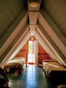 a attic room with two beds and a window at La Campiña Cabañas in Santa Rosa de Calamuchita