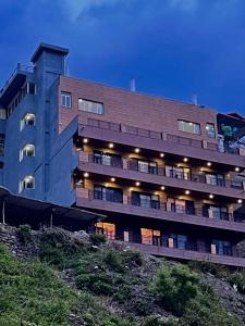 a large building with lights on the side of it at River Grand Resort - A Peaceful Stay Kempty Fall Mussoorie in Mussoorie