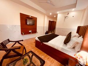 a bedroom with a bed and a tv on the wall at River Grand Resort - A Peaceful Stay Kempty Fall Mussoorie in Mussoorie