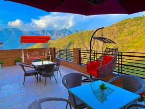 a patio with tables and chairs and an umbrella at River Grand Resort - A Peaceful Stay Kempty Fall Mussoorie in Mussoorie